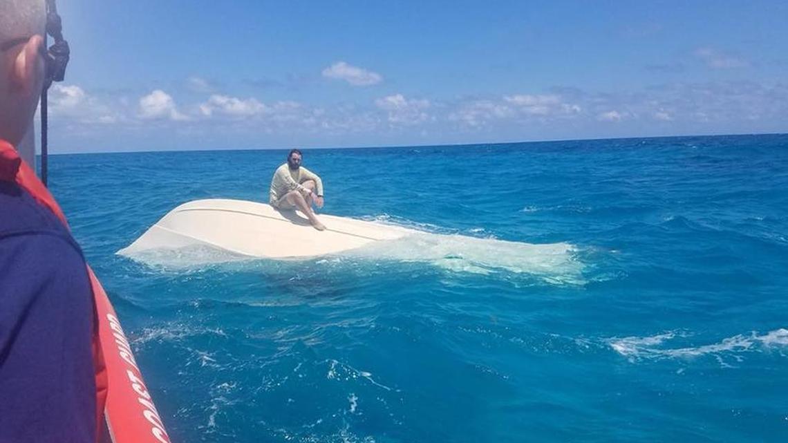A U.S. Coast Guard crew approaches a man sitting on a capsized boat off Islamorada on Saturday, April 7, 2018.