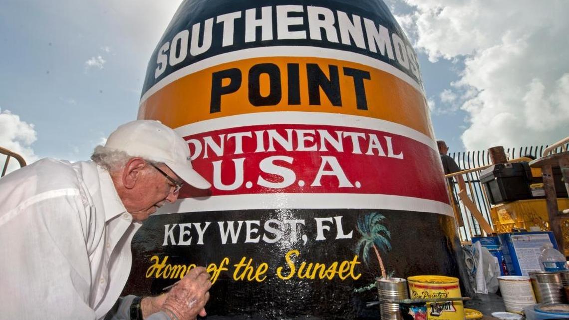 In this photo provided by the Florida Keys News Bureau, artist Danny Acosta completes lettering the Key West buoy, which reads, “90 Miles to Cuba. Southernmost Point in the Continental U.S.A., Key West, FL,’’ on Monday, Oct. 23, 2017. Hurricane Irma pummeled one of the most-photographed tourism icons in the Florida Keys on Sept. 10, 2017, stripping most of the paint and a large chunk of stucco.