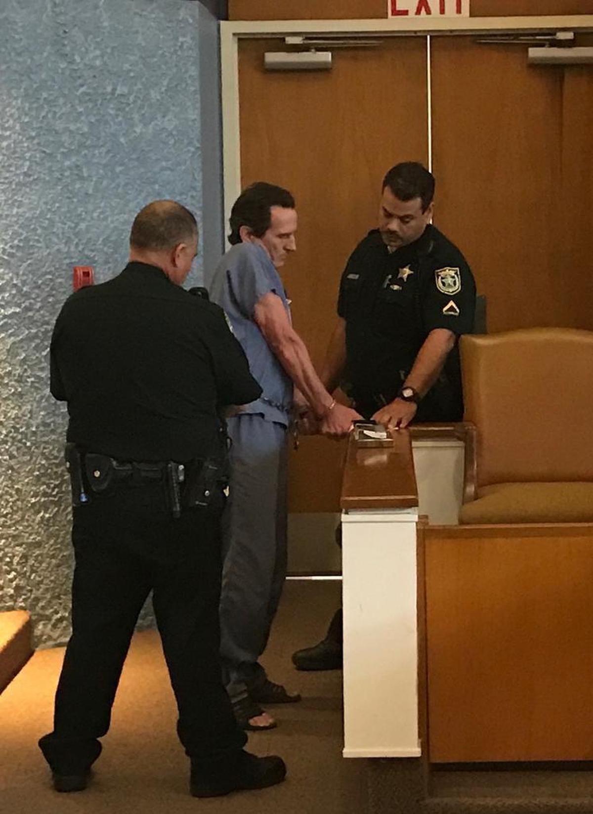 Monroe County Sheriff’s Office deputies take fingerprints from a shackled Robert Schminky.