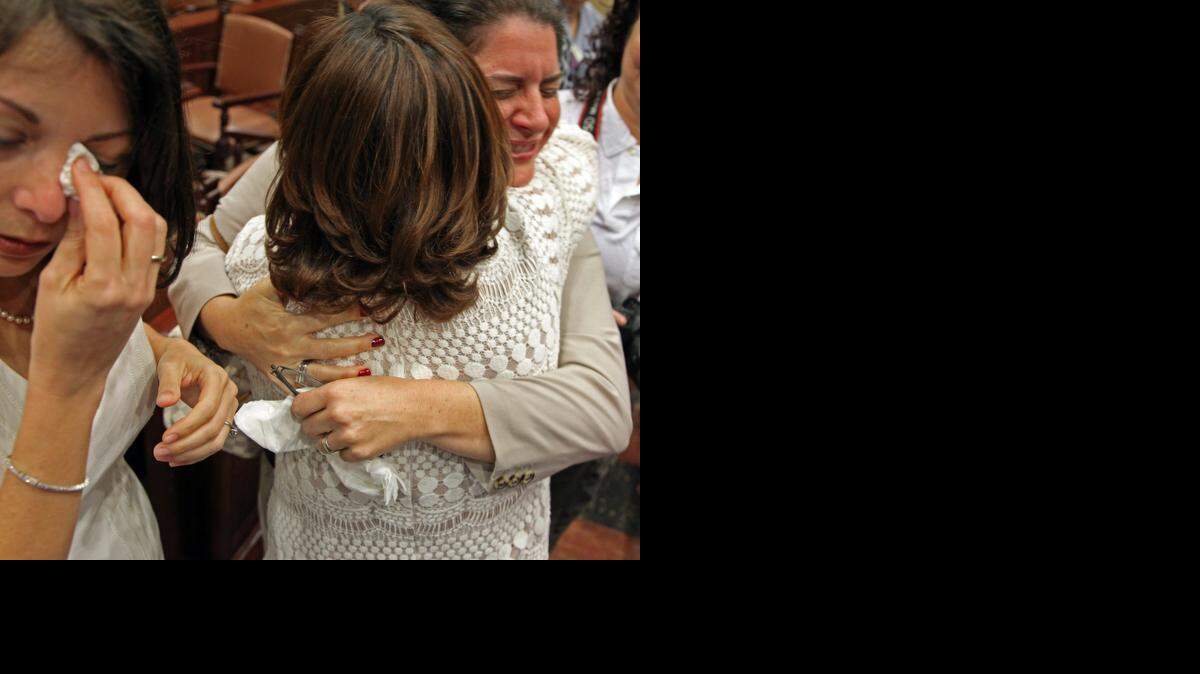 
Attorney Elizabeth Schwartz, right, hugs Karla Arguello, who married Catherina Pareto, left, in court after Judge Sarah Zabel lifted the stay, allowing same-sex couples to marry on Monday, Jan. 5, 2015.
