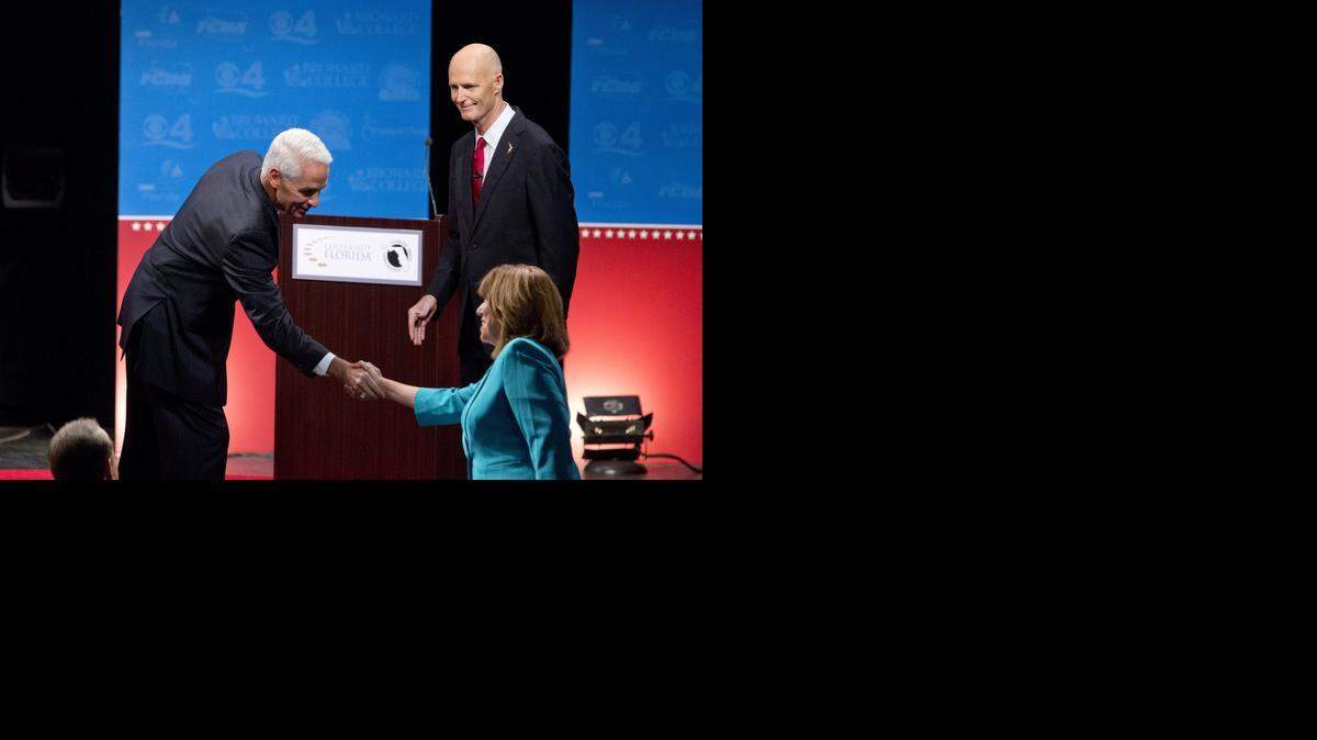 
Democratic challenger, former Republican Gov. Charlie Crist, left, and Florida Republican Gov. Rick Scott, right, shake hands with moderator Rosemary Goudreau after a debate, Wednesday, Oct. 15, 2014 in Davie, Fla.
