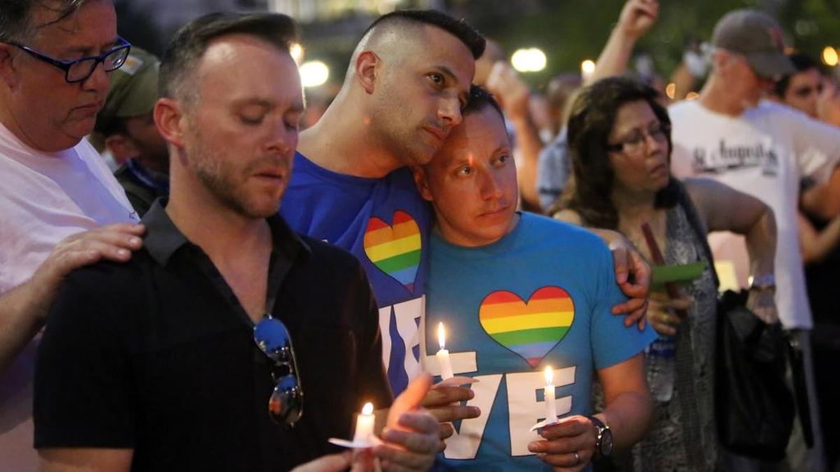 From left, Travis Morris, Paul Odom, Bobby Bongiorno and Eric Ferrari hold candles and observe a moment of silence along with thousands of others who attended a vigil for the victims of the Pulse nightclub shooting. The vigil was on the lawn of the Dr. Phillips Center for the Performing Arts, Monday evening, June 13, 2016.
