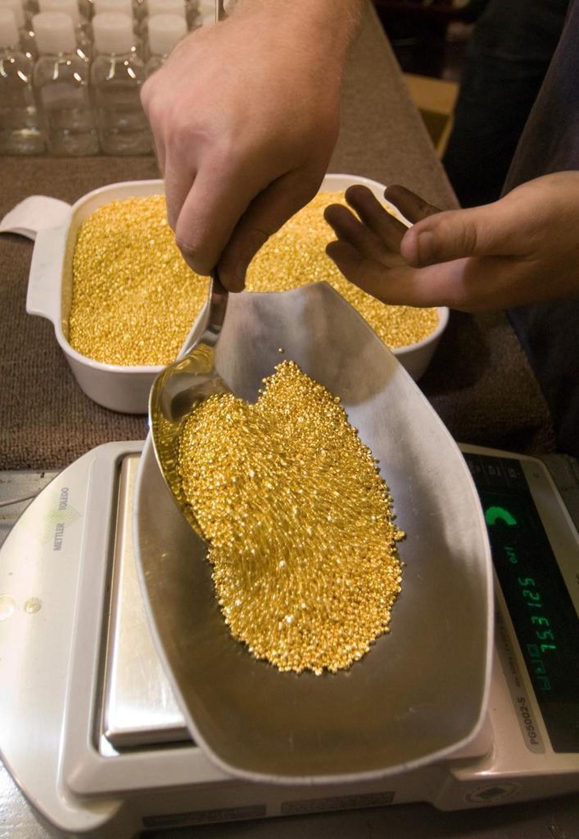 A worker scoops grains of pure gold onto a scale for weighing before packaging and shipment at Ohio Precious Metals in Jackson, Ohio, in 2006.