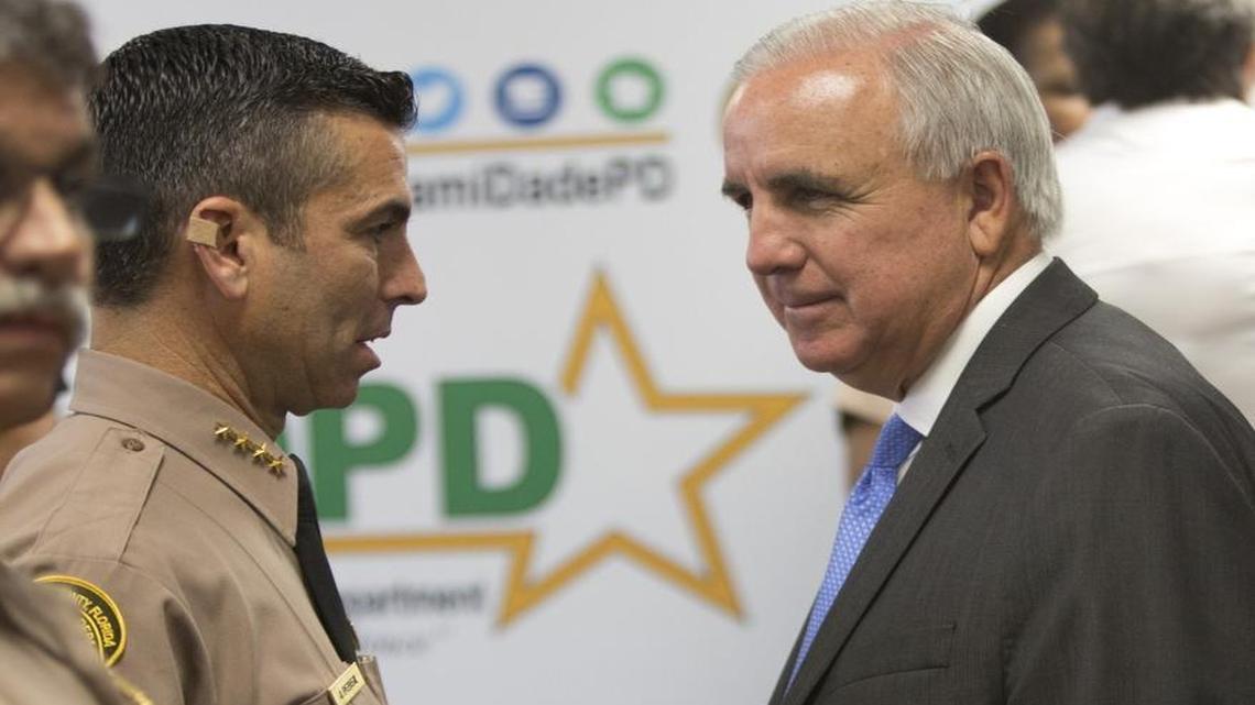 Juan Perez, director of the Miami-Dade Police Department, speaks with Miami-Dade Mayor Carlos Gimenez, following a press conference on body cameras on Thursday, April 28, 2016.