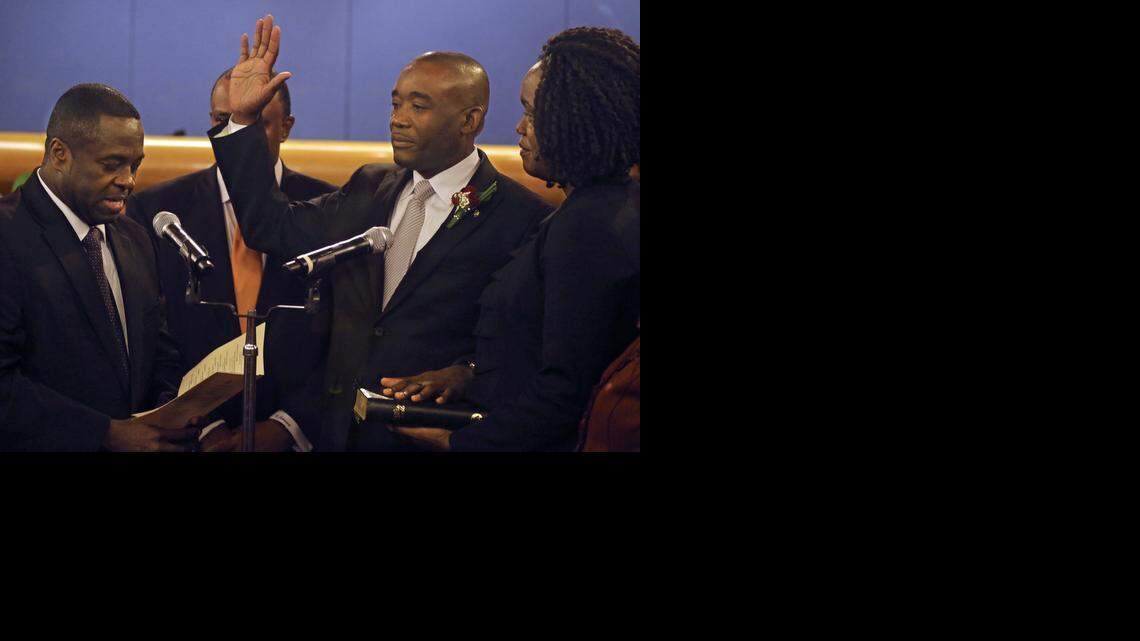 
Jean Monestime, standing next to his wife, Kettia, is sworn into office by the Rev. Leslie Moise.
