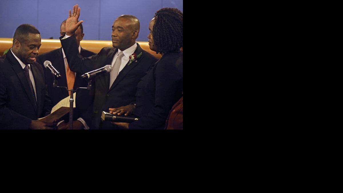 
Jean Monestime, standing next to his wife, Kettia, is sworn into office by the Rev. Leslie Moise.
