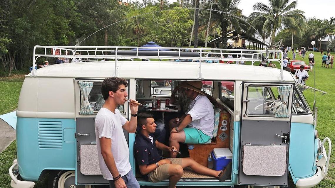 From left, Daniel Isaia, 22, Anthony Torres, 18, and Alejandro Leal, 18, enjoy cigars beside a 1967 Volkswagen bus on Sunday during the Barnacle Historic State Park’s Father’s Day celebration called “Cars and Cigars.”