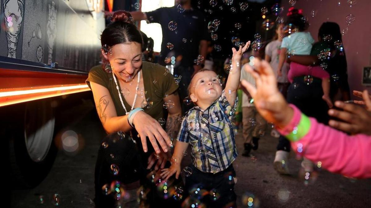 Lacey Thompson and her son Dylan enjoy playing with soap bubbles as the Amazon's Treasure Truck paid a surprise visit to Lotus House on Thursday, Dec. 7, 2017, to provide the children with some holiday fun, including a winter wonderland of festive music, games, a photo booth, holiday treats — and even some falling snow. Lotus House is one of more than 30 stops across the country that Amazon is doing to bring holiday cheer to groups that work with families and children.