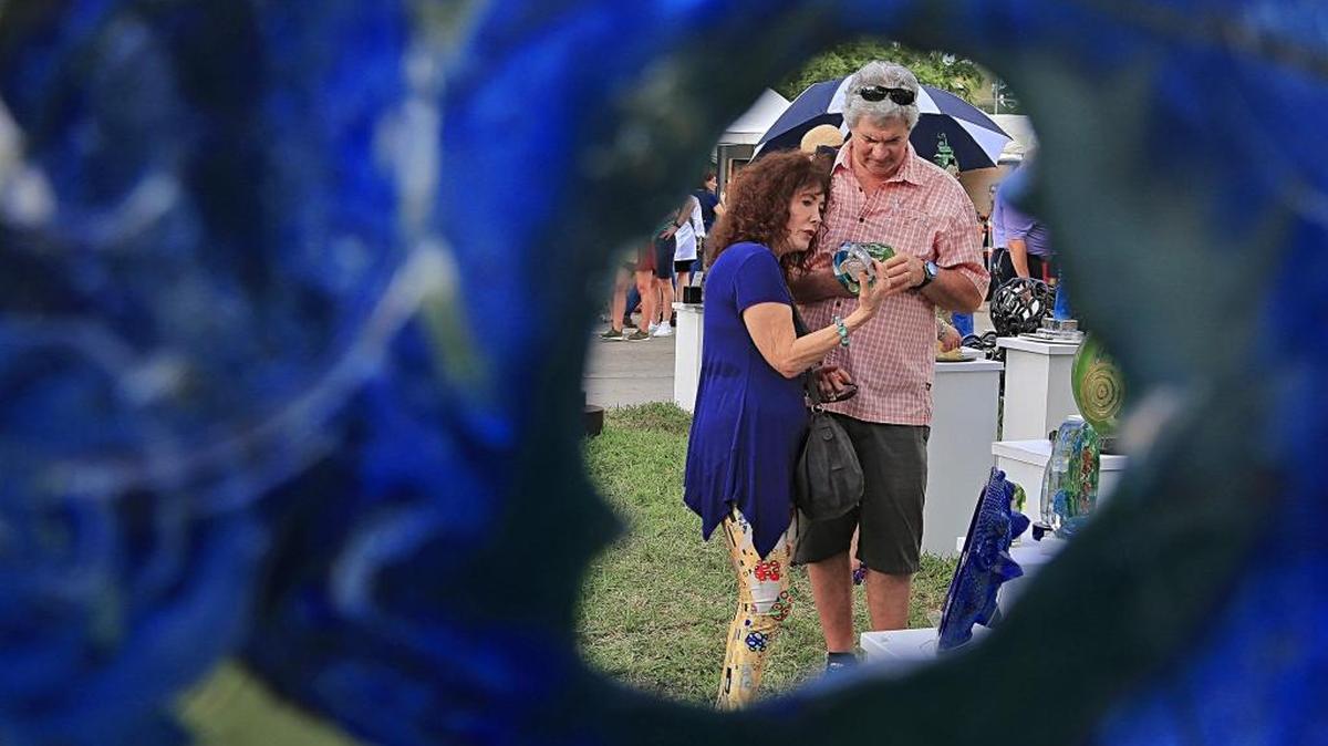 Marlene Tobias, left, and her husband David Tobias, right, examine the glass work by Susan Gott at the Coconut Grove Art Fair Sunday, Feb. 19, 2017,.
