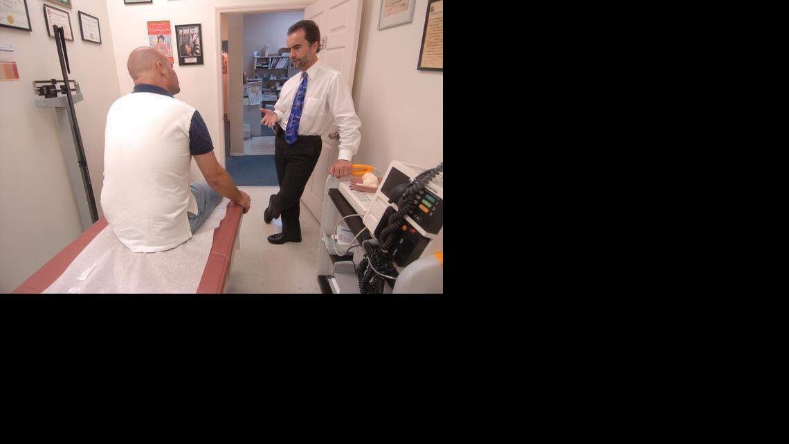 
Dr. Bernd Wollschlaeger speaks to a patient at his North Miami Beach practice in 2007. Wollschlaeger, a family medicine doctor, has had to educate consumers who know little about their Affordable Care Act coverage plans while also juggling a higher patient load, more paperwork and issues with reimbursement since the passage of the act. 
