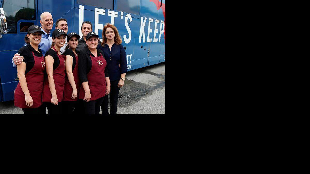 
Florida Gov. Rick Scott poses with Ankarr European Pastry Shop waitresses Joeline, Yoana, Karla, Nuria and Jorge, plus owners Amylcar and Daysel Arredondo during a campaign stop on Wednesday, Oct. 22, 2014.

