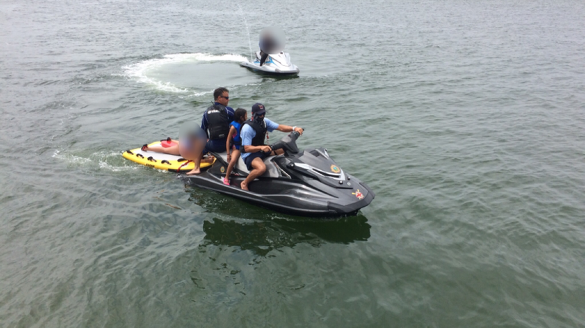 Two lifeguards rescue a man and two children Sunday from an overturned Jet-Ski in the waters near Haulover Cut.