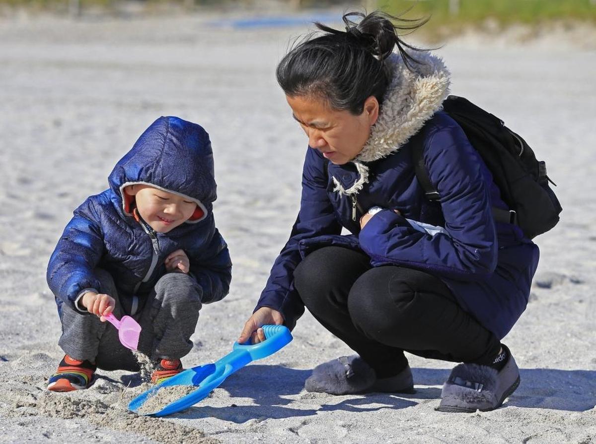 A bundled-up Shuo Tao Wu, 4, plays in the sand with his mother, Xiang Rong Bao, while vacationing in South Beach on Thursday.