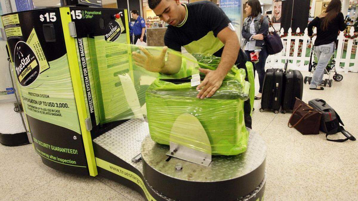 Competition is fierce for the lucrative airport baggage wrap contract at Miami International Airport. Ronald Graveran, with TrueStar SecureBag, wraps a piece of luggage in this file photo taken December 14, 2011.