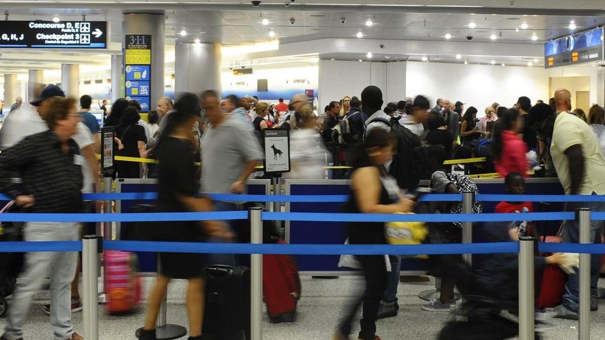 Local and international travelers wait in line for the security checkpoint at the Miami International Airport.