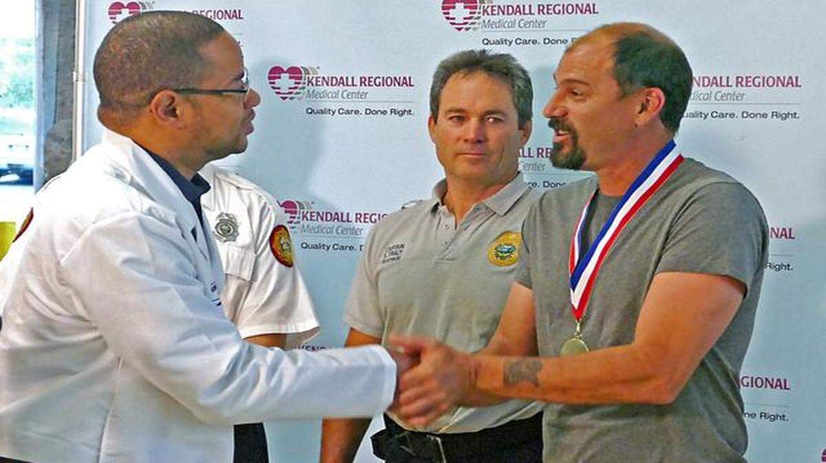 
Anthony Toledo receives a trauma survivor award from Kendall Regional Medical Center trauma surgeon Mark Cockburn on Tuesday.


