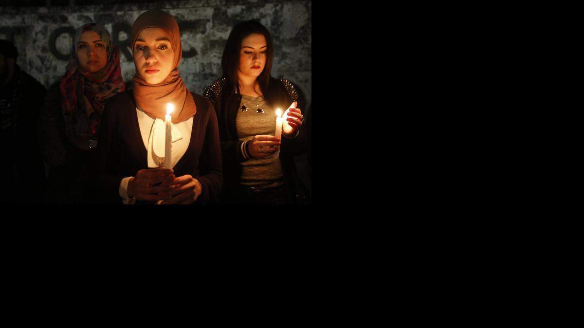 
Eman Abdelhamid, center, 24, of Pembroke Pines, stands in vigil with Nour Haykal, right, at the Torch of Friendship for a candlelight vigil in remembrance of the three people of Muslim faith that were killed in Chapel Hill, Thursday, Feb. 12, 2015.
