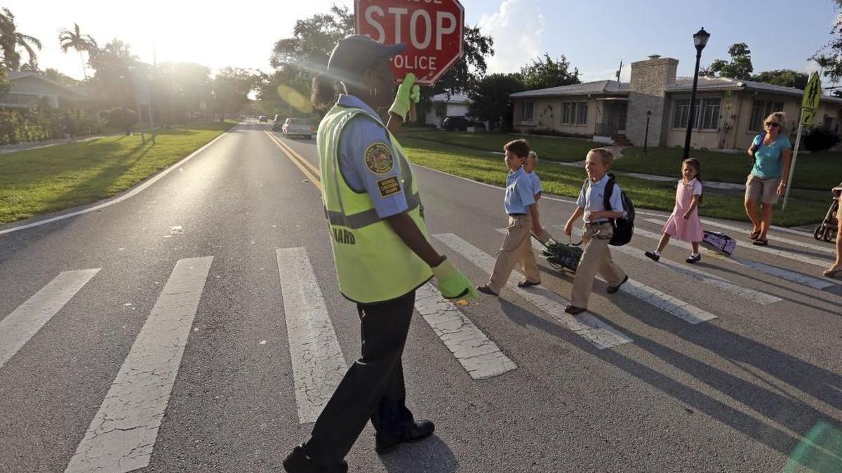 Crossing Guard, Berenise Monestime makes sure students cross NE 103rd St. at Fourth Ave. as they make their way to St. Rose of Lima Lima Catholic School in Miami Shores in this 2013 file photo.