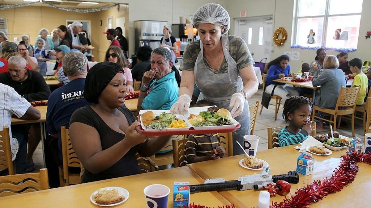 Ms. Fisher a volunteer with the Greater Miami Jewish Federation serves Christmas lunch to Albany Patrick and her kids residents at Miami Rescue Miami on Christmas Day on Monday, Dec. 25, 2017.