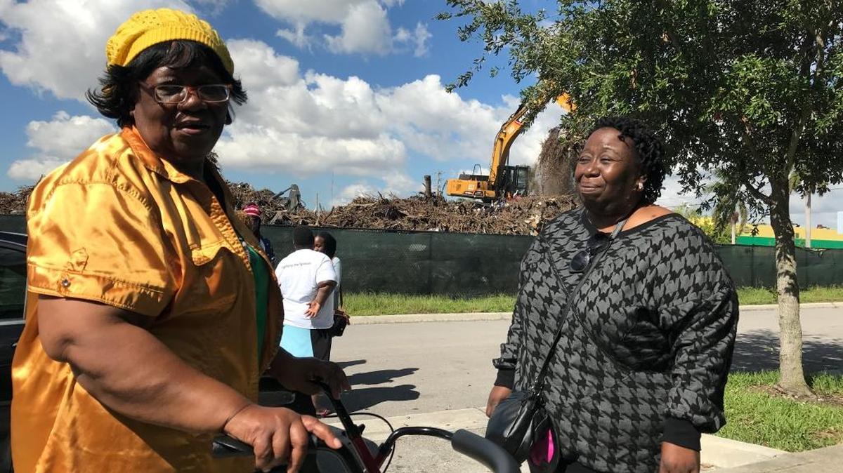 Helen Clarke, left, and Joanna Janvier outside the Northpark at Scott Carver apartment complex while a crane across the street hauls storm debris from Hurricane Irma. Miami-Dade opened a massive debris dump next to the housing complex in October, but has halted more shipments there after resident complaints.