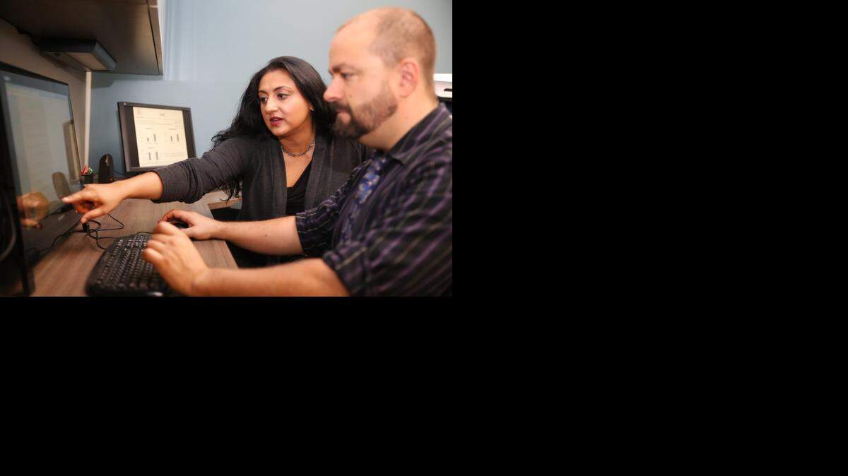 
University of Miami neuroscientist Amishi Jha points out information on a powerpoint presentation with Martin Paczynsk, a member of her research team.

