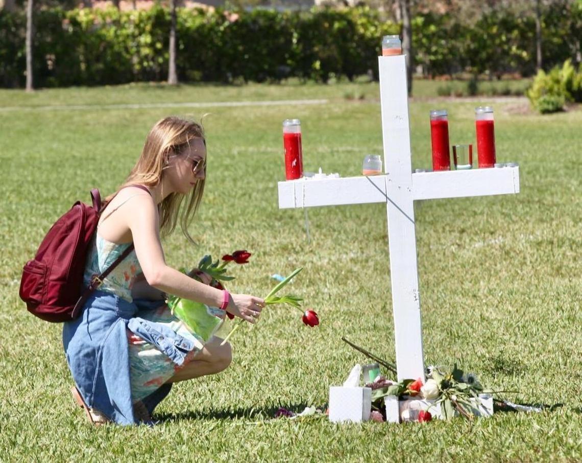 Hannah Morley, 19, offers a rose at a memorial for the 17 people shot and killed at Marjory Stoneman Douglas High School on Wednesday, Feb. 14, 2018. On Friday, Feb. 16, 2018, she was at Pine Trails Park in Parkland in Broward County, where the victims were being honored.
