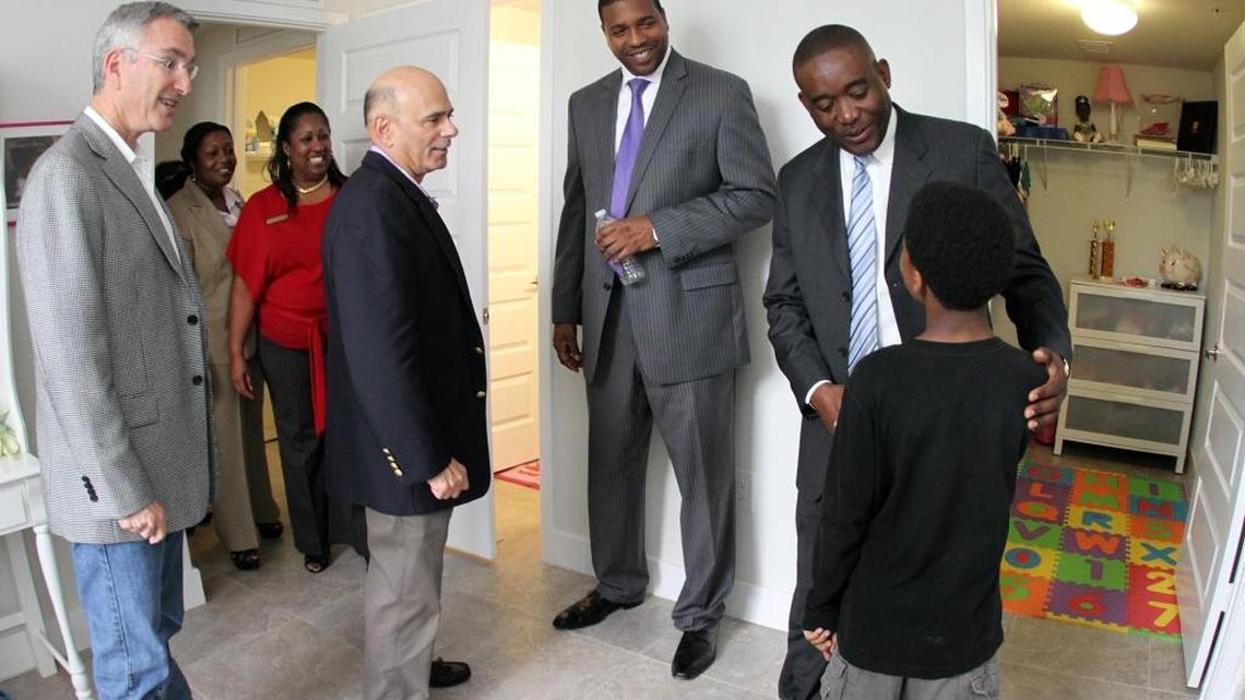 From left, David O. Deutch, Mitchell M. Friedman, partners at Pinnacle Housing Group, join Miami-Dade officials for a 2013 opening of a subsidized Pinnacle project, Kings Terrace, near Opa-locka. An affiliate of the company later ran afoul of state and federal regulators over alleged padding of contracts, including one using Miami-Dade tax dollars. In 2018, the company is up for more county dollars. Also in the picture, Russell Benford, center, then a deputy county mayor, and Miami-Dade Commissioner Jean Monestime, far right. They’re greeting young resident Joshua Hamilton, age 9, inside his sister's room at the family’s new home.