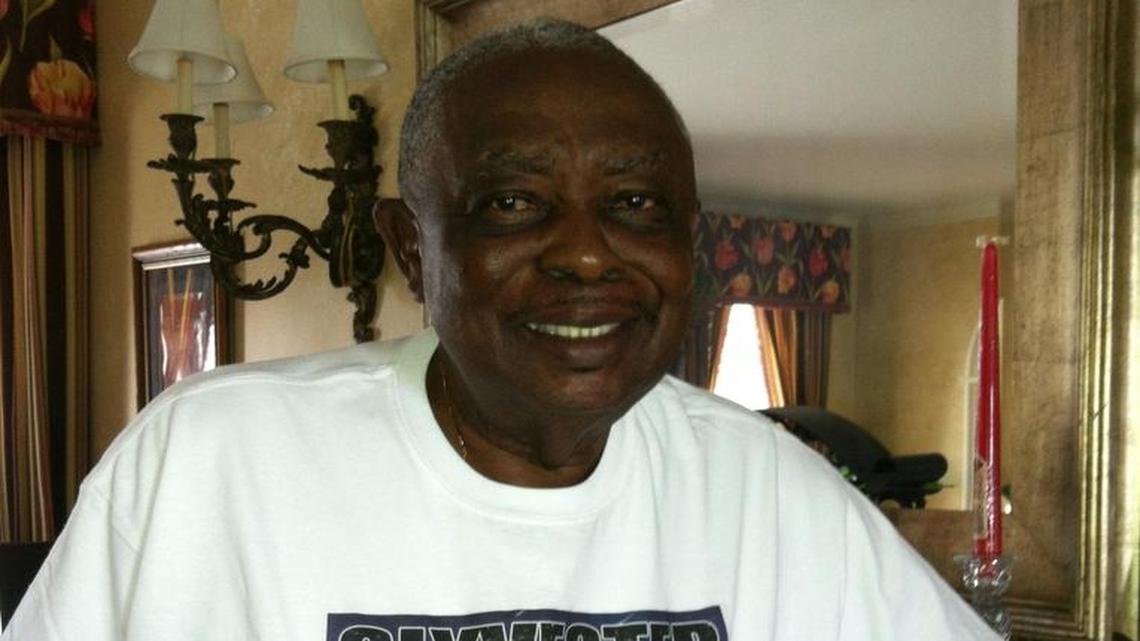 Sylvester Collier at home in Ocilla, Georgia, is preparing to reunite with Miami youth he mentored more than 40 years ago. He is wearing a T-shirt with a photo of himself with sons Tracy, Ricky and Gregory Collier.