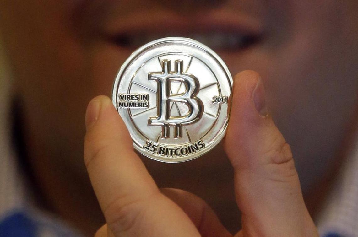 In this April 3, 2013 photo, Mike Caldwell, a 35-year-old software engineer, holds a 25 Bitcoin token at his shop in Sandy, Utah. Bitcoin is an online currency that allows people to make one-to-one transactions, buy goods and services and exchange money across borders without involving banks, credit card issuers or other third parties.
