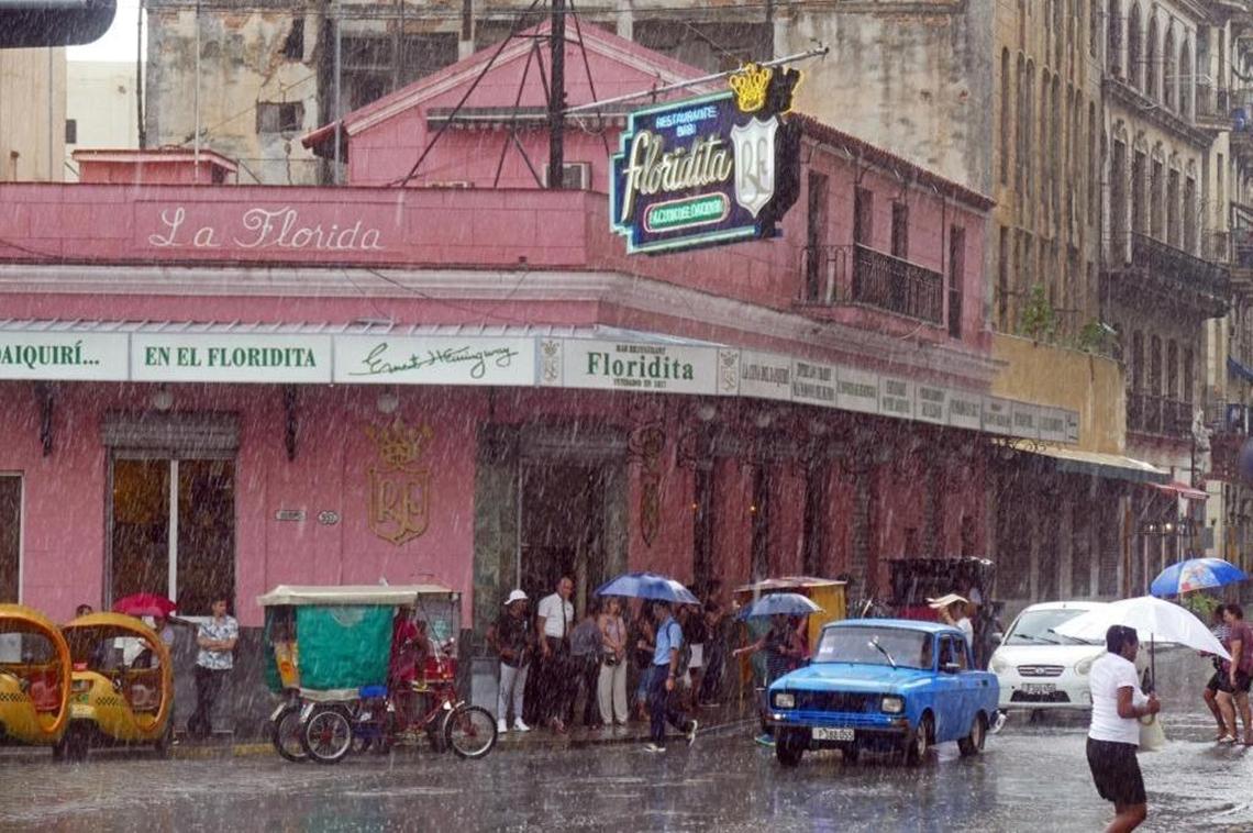 Tourists and locals try to keep dry under the awning of the Floridita in Old Havana during a downpour Tuesday afternoon, Sept. 26, 2017.