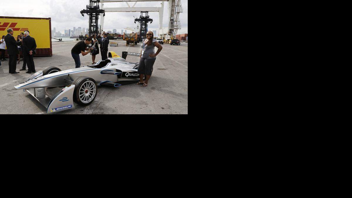 
 Clare Shikyma, executive secretary of business initiatives for PortMiami, stands next to one of the electric race cars that will be racing in the Miami ePrix on March 14, 2015. 
