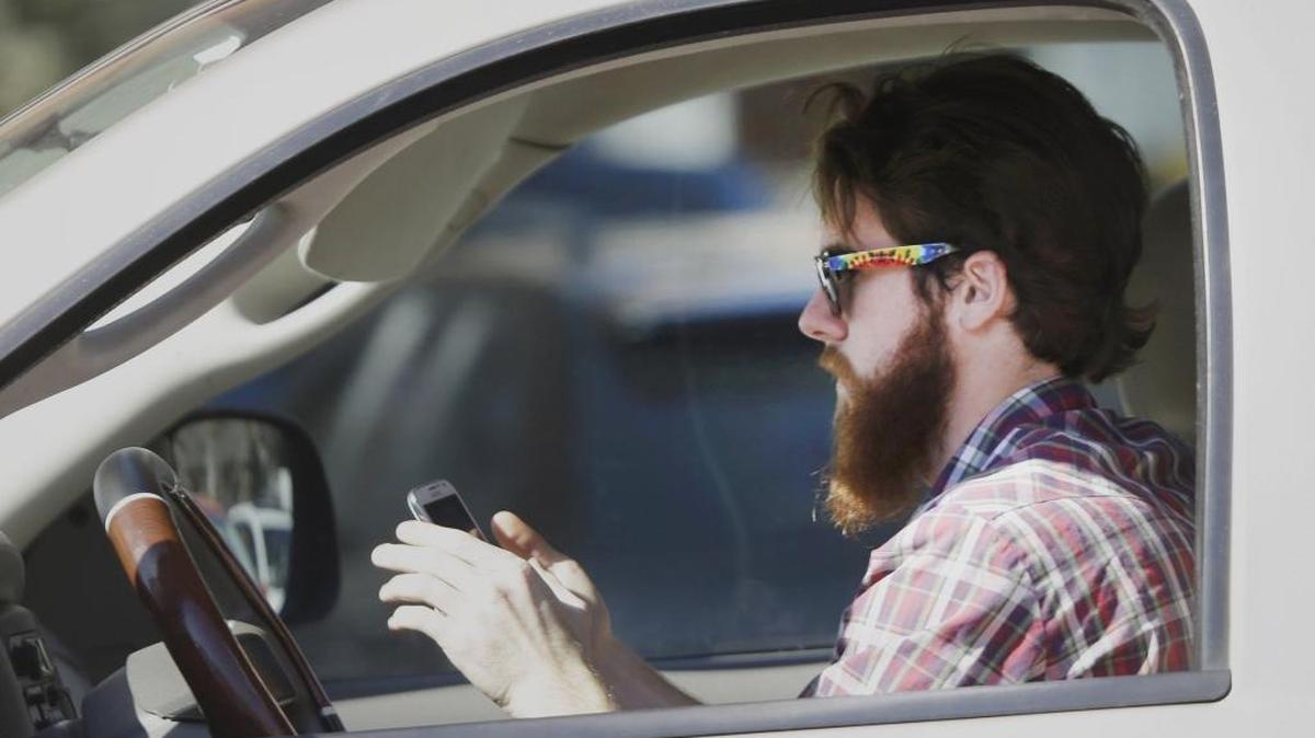 In this file photo, a man uses his cellphone as he drives through traffic.