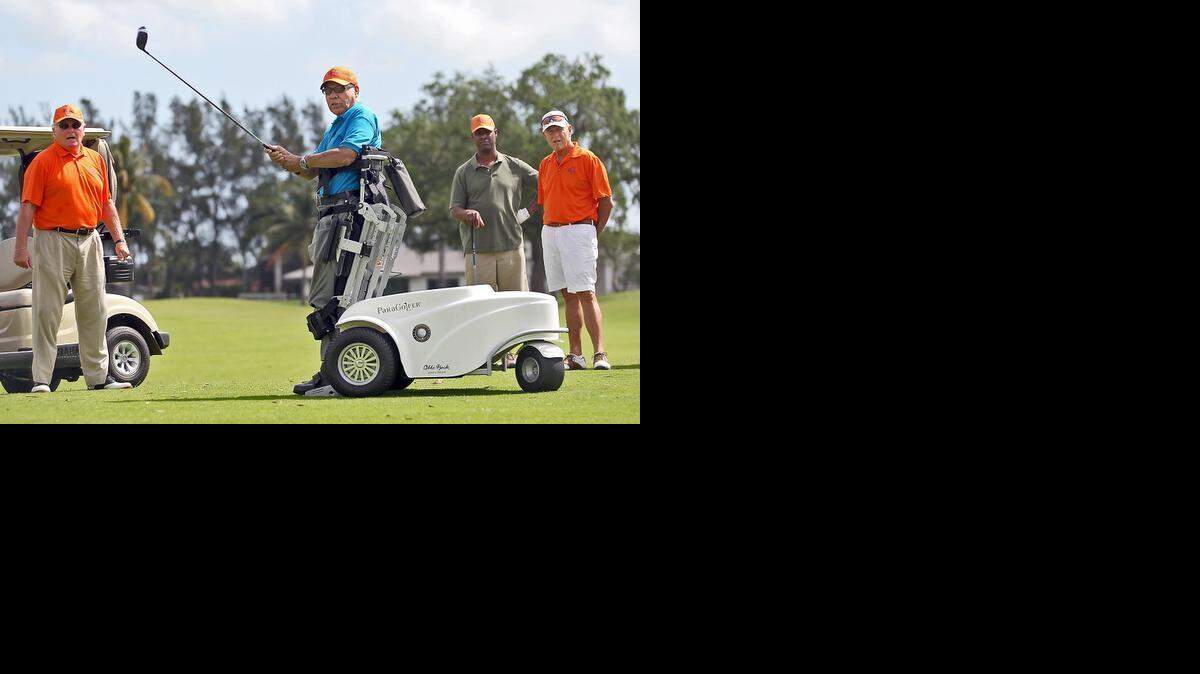 Veteran Ralph Carbello uses a standing wheelchair to hit a fairway shot as instructors Jim Rondeau and Mark Alpert, both in orange, and fellow veteran Mozell Mann look on at the Melreese Country Club in Miami on Wednesday, March 4, 2015.