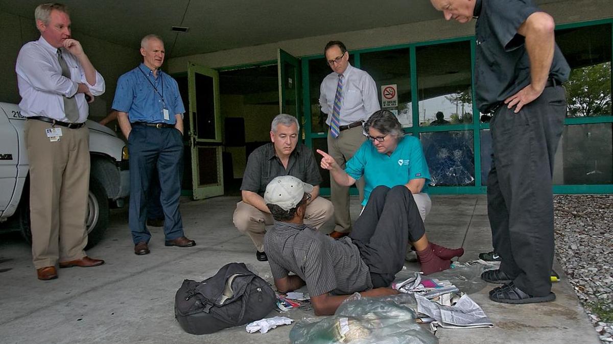 Camillus House CEO Shed Boren, in the black shirt, kneels down to talk to Amos Moss as Miami-Dade Circuit Judge Steve Leifman (rear, in white shirt) gives a tour of a site for a new mental-health facility in Miami in this 2014 file photo.