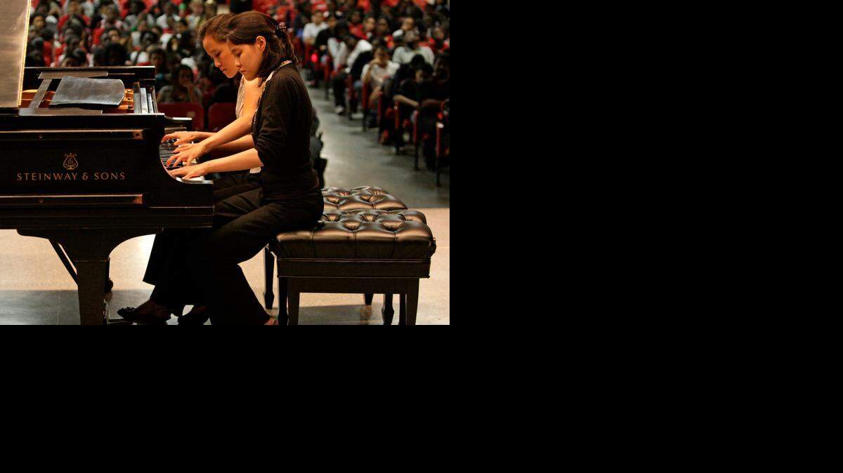 
SISTER ACT: Twin pianists Susan and Sarah Wang perform in front of students at Brownsville Middle School in 2009. They will perform Dec. 21 in Aventura. 
