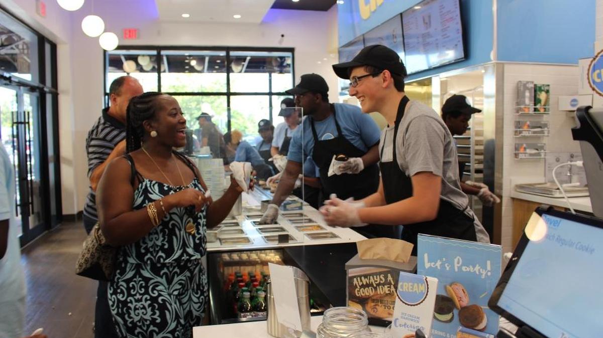Armando Martinez Jr. serves Nakita Walker of Miami Gardens a free ice cream cookie sandwich as part of CREAM's grand opening celebration on May 7.