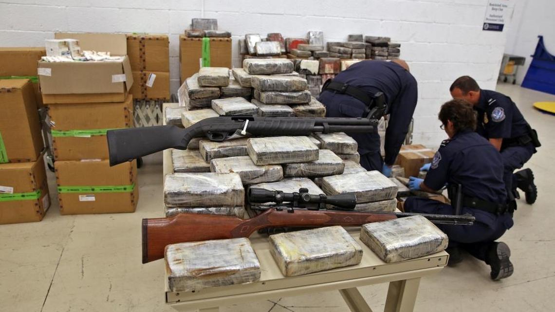 Customs agents review evidence of seized weapons.