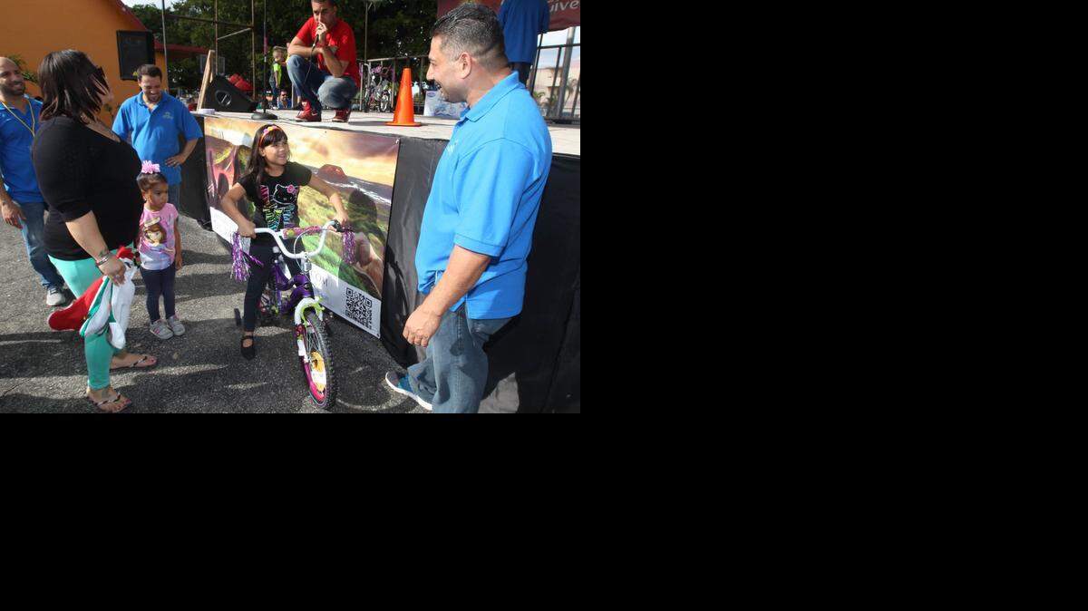 
Miguel Mendez, (right, blue shirt) a former Miami gang members, and now the director of Second Chance Youth Outreach, gives a bike to Angelysse Delvalle, (center on bike). Miguel and other ex-gang membetrs gave toys, bikes, and books, away for the holidays to underprivledged youth at the Casa de Alabanza, in Hialeah.
