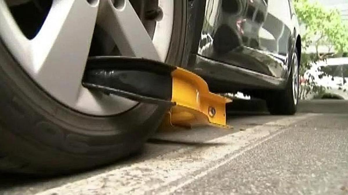 A metal boot attached to a wheel is used to immobilize a parked car.
