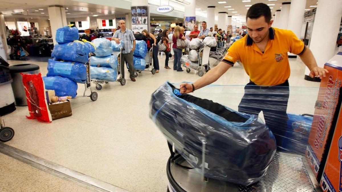 
Wrapping luggage in plastic for protection on international flights is big business at Miami International Airport. Travelers preparing to fly to Cuba from MIA in this 2009 file photo get their luggage wrapped before their flight. 
