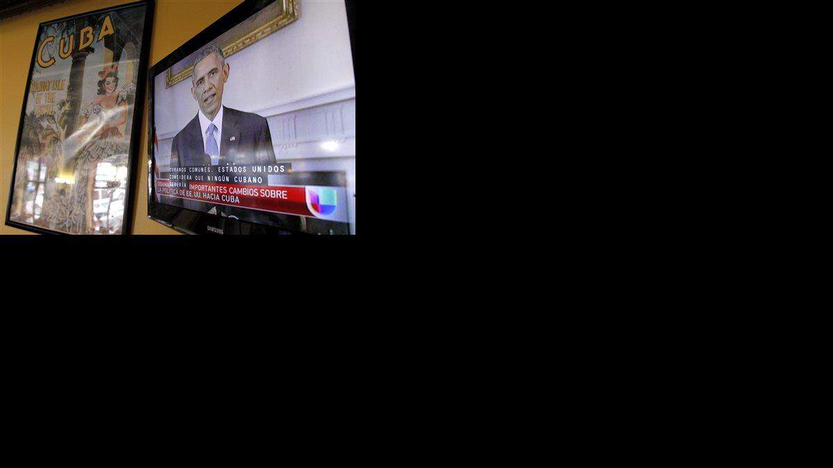 President Barack Obama is shown on a television screen with Spanish captions as a Spanish language television network shows his speech live inside a Cuban coffee shop, Wednesday, Dec. 17, 2014, in Union City, N.J. Obama announced the re-establishment of diplomatic relations and an easing in economic and travel restrictions on Cuba Wednesday, declaring an end to America's "outdated approach" to the communist island in a historic shift aimed at ending a half-century of Cold War enmity.