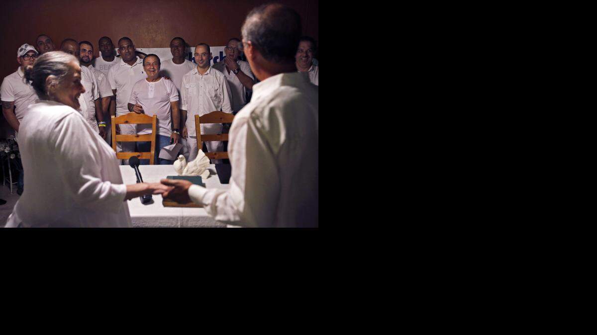 
Founders of Church of Babalú Ayé, Carmen Rodriguez, left, and son, Ernesto Pichardo, right, hold hands as Pichardo announces the unification of his church with Kola Ifa Miami. Ceremony organizers say the partnership is aimed at making Miami and Cuban's Lukumi, or Santeria, community more mainstream and less mysterious to the public and to differentiate the faith from back-to-Africa practitioners.
