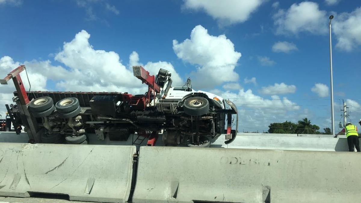 A truck lies tipped over along State Road 836, by Northwest 37th Avenue, on Wed., Oct. 11, 2017. A dispatcher with the Miami Fire Department said a man on the truck was injured from a fall during the incident.
