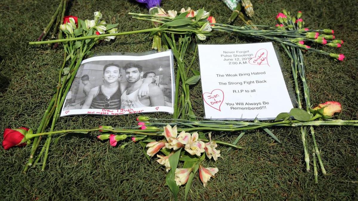 These are flowers and the photo were left by Chris Drozd and Stefan Salvatore as they memorialized three friends of their friends who were killed at Pulse nightclub in Orlando.
