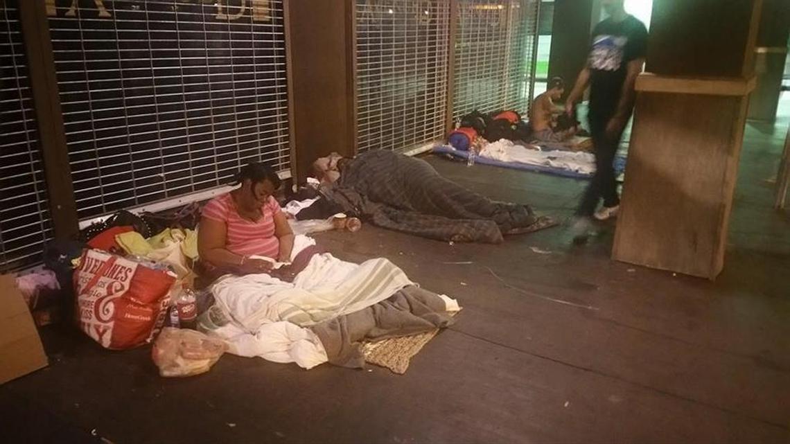 A woman reads from a Bible on the sidewalk along Southeast First Street, a strip downtown where homeless men and women congregate every night.