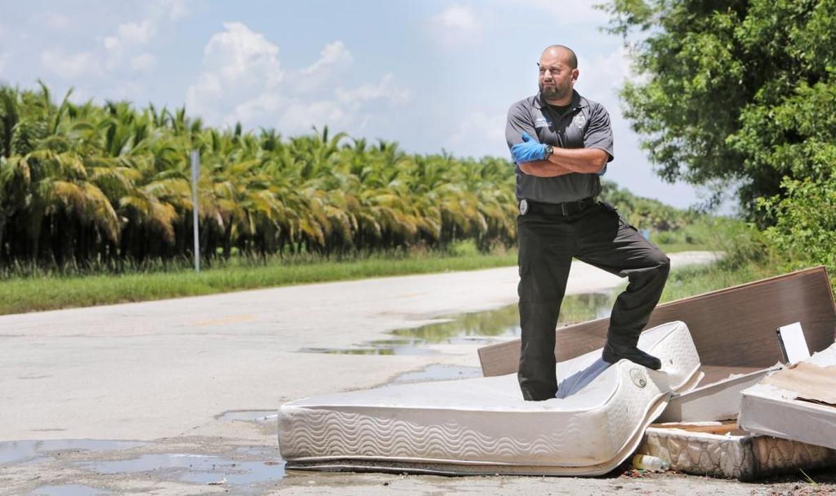 Santiago Callejas stands atop a pile of mattresses left along Southwest 107th Avenue. The investigator for Miami-Dade’s Solid Waste division tries to track down people responsible for illegal dumping.