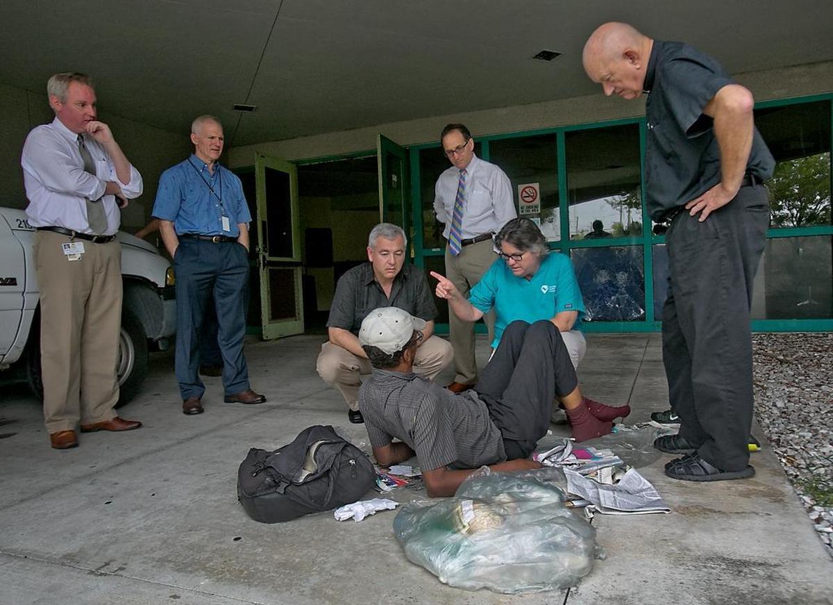 Camillus House CEO Shed Boren, in the black shirt, kneels down and talks to Amos Moss as Miami-Dade Circuit Judge Steve Leifman (rear, in white shirt) gives a tour of a site for a new mental-health facility in Miami in this 2014 file photo.
