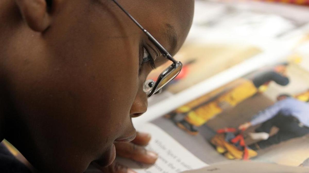Second grader Lawrence Murray, age 8, reads from one of his text books wearing his brand new glasses at David Lawrence Jr. K-8 Center.