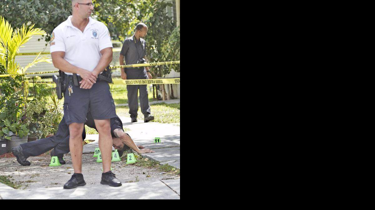 
A Miami police detective leans down to check a bullet casing as he investigates a shooting at 3452 Day Ave. in Coconut Grove on Monday, Feb. 23, 2015.
