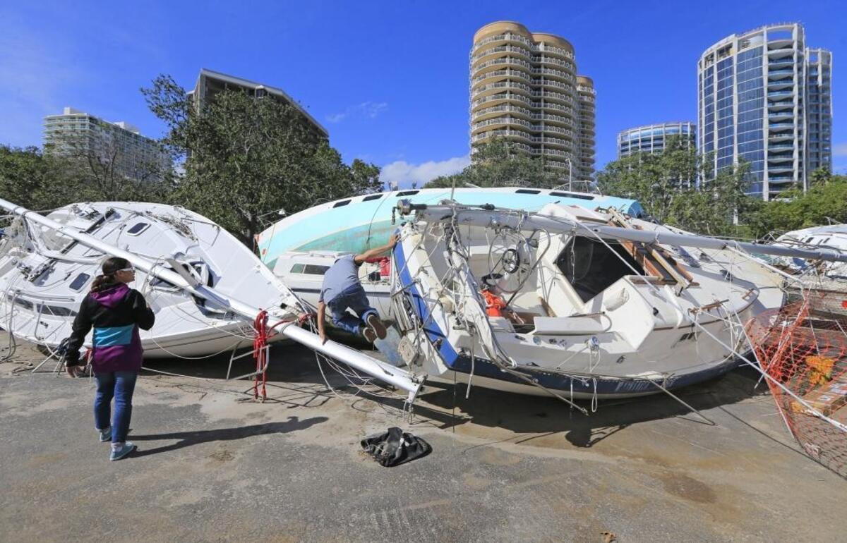 Hugo Hernandez and Elizabeth Devesa check out the boat graveyard sitting in the Dinner Key marina parking lot on Tuesday, Jan. 16, 2018. Boats damaged and abandoned after Hurricane Irma are stacked up to be demolished. Hernandez wonders whether he can buy one of the abandoned boats.